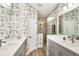 Elegant bathroom with dual vanities, walk-in shower, and decorative wallpaper at 11265 Mc Dermott Ct, Englewood, FL 34223