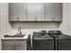 Modern laundry room with gray cabinets, patterned wallpaper, and new appliances at 11265 Mc Dermott Ct, Englewood, FL 34223