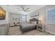 This bedroom features a tray ceiling, ceiling fan, wood-look floors, and stylish decor at 17744 Savory Mist Cir, Bradenton, FL 34211