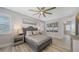 This bedroom features a tray ceiling, ceiling fan, wood-look floors, and stylish decor at 17744 Savory Mist Cir, Bradenton, FL 34211