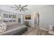 This bedroom features a tray ceiling, ceiling fan, wood-look floors, and stylish decor at 17744 Savory Mist Cir, Bradenton, FL 34211