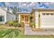 Front entrance of a yellow house with orange door and landscaped garden at 3541 Blechnum Fern Ln, Sarasota, FL 34235