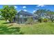 The backyard has a screened-in pool with chairs for relaxing and landscaping on a sunny day at 4409 Eleuthera Ct, Sarasota, FL 34233