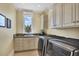 Well-appointed laundry room with white cabinets and modern appliances at 507 Casey Key Rd, Nokomis, FL 34275