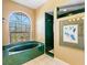 Bathroom featuring large bathtub with green tile, tiled shower, and natural light from a window at 508 Siesta Dr, Sarasota, FL 34242
