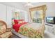 Bright bedroom with floral bedding, mirrored closet, and wicker chair at 508 Siesta Dr, Sarasota, FL 34242