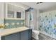 Bathroom with blue-tile accents, white toilet and vanity, and patterned shower curtain at 6710 36Th E Ave # 384, Palmetto, FL 34221