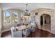 A dining room with arched windows, a chandelier, exposed brick, and hardwood floors at 8855 Midnight Pass Rd, Sarasota, FL 34242