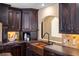 Kitchen with dark wood cabinets, double copper sink, and decorative tile backsplash at 8855 Midnight Pass Rd, Sarasota, FL 34242