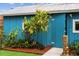 Close-up of blue outbuilding with tropical landscaping and tiki statue at 105 Tucker Ave, Sarasota, FL 34232