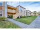 Exterior view of a two-story condo building with a walkway, lush landscaping, and palm trees at 1130 Villagio Cir # 203, Sarasota, FL 34237