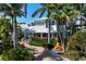 Two-story home with a metal roof, lush landscaping, and a brick paver driveway at 116 50Th St, Holmes Beach, FL 34217