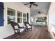 Spacious front porch with rocking chairs, a porch swing, and ceiling fans at 116 50Th St, Holmes Beach, FL 34217