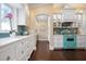 Well-equipped kitchen with white cabinets, turquoise stove, and dark hardwood floors at 116 50Th St, Holmes Beach, FL 34217