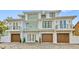 Striking three-story coastal home featuring a symmetrical design, three-car garage, and charming Juliette balconies at 329 Tarpon St, Anna Maria, FL 34216