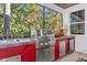 Outdoor kitchen with stainless steel grill, sink, and red cabinetry at 750 Foggy Morn Ln, Bradenton, FL 34212