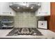 Gas cooktop with stainless steel hood and light green tile backsplash at 5706 Bent Oak Dr, Sarasota, FL 34232