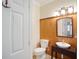 Half bathroom with wood-paneled walls, white toilet, pedestal sink, and a mirror at 7945 Palmer Blvd, Sarasota, FL 34240