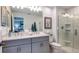 Bathroom with double vanity, shower, and gray cabinets at 8728 Winter Breeze Way, Sarasota, FL 34241