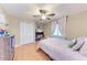 Bedroom features wood-look floors, ceiling fan, and a closet, with a window covered in light-colored curtains at 9363 Steubenville Ave, Englewood, FL 34224