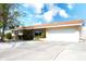Tan single story house with a white garage door and landscaped yard at 9820 Royal Palm Dr, Bradenton, FL 34210