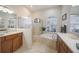 Bright bathroom features a soaking tub, glass shower, double sink vanity, and neutral tile throughout at 12343 Lavender Loop, Bradenton, FL 34212