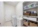 Bright laundry room features a modern washer and dryer, utility sink, and built-in storage shelves for organization at 12343 Lavender Loop, Bradenton, FL 34212