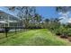 Expansive backyard with black metal fence, lush green lawn, and partial view of pool at 3930 Elysian Woods Ln, Sarasota, FL 34231