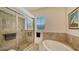 Bright bathroom features a large glass shower, soaking tub and natural light from the window at 3930 Elysian Woods Ln, Sarasota, FL 34231
