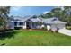 Charming home featuring a metal roof, green lawn, and mature landscaping at 3930 Elysian Woods Ln, Sarasota, FL 34231