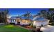 Lovely home with metal roof, well-lit landscaping, and manicured lawn at dusk at 3930 Elysian Woods Ln, Sarasota, FL 34231