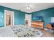 Bedroom showcasing blue accent wall, a dresser with a TV, and an open doorway to an attached bathroom at 5111 26Th St. Ct, W # 53, Bradenton, FL 34207