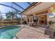 Inviting pool area with covered patio, outdoor kitchen, and lush landscaping at 7443 Riviera Cv, Lakewood Ranch, FL 34202