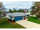 Exterior view of a cozy home featuring a blue garage door, a flag and lush landscaping at 1121 Danny Dr, Sarasota, FL 34243