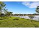 Scenic view of the backyard extending to a serene lake, enhanced with a wrought iron fence and lush green lawn at 13789 Old Creek Ct, Parrish, FL 34219