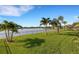 Beautiful backyard featuring a waterfront view, lush grass, and palm trees, creating a serene outdoor space at 13789 Old Creek Ct, Parrish, FL 34219