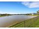 Tranquil view of a serene lake, complemented by lush greenery and a secure wrought iron fence at 13789 Old Creek Ct, Parrish, FL 34219