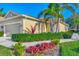 Front exterior view of a home with a one-car garage, lush landscaping, and palm trees at 2520 Terracina Dr, Venice, FL 34292