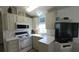 Kitchen with white appliances, light green cabinets, and a flat-screen TV mounted on the corner at 3333 26Th E Ave # 1107, Bradenton, FL 34208