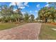 Brick paved driveway leading to a house surrounded by palm trees at 5105 Bannock Cir, North Port, FL 34288