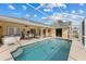 Pool area with screened enclosure, hot tub, dining set, and view of the home's exterior at 5105 Bannock Cir, North Port, FL 34288