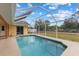 Pool and screened enclosure with view of the grassy backyard, under blue skies at 5105 Bannock Cir, North Port, FL 34288