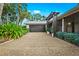 Attached garage with dark gray door and landscape at 5345 Siesta Ct, Sarasota, FL 34242