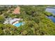 Aerial view featuring a pool and community center surrounded by lush trees and a waterfront at 5611 Key West Pl # 5611, Bradenton, FL 34203
