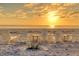 Serene beach setting featuring six Adirondack chairs perfectly positioned to enjoy the sunset at 5965 Gulf Of Mexico Dr, Longboat Key, FL 34228