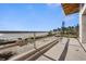 Beach view from the upper floor of the home, featuring sand, palm trees, blue ocean, and a clear sky at 5965 Gulf Of Mexico Dr, Longboat Key, FL 34228