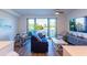 Living room with blue couch, wood floors, sliding glass door to balcony, and wall-mounted TV at 1709 N Tamiami Trl # 214, Sarasota, FL 34234