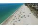 Sandy beach with clear turquoise waters, people sunbathing, and colorful umbrellas at 2835 N Beach Rd, Englewood, FL 34223