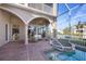 Covered outdoor patio with a canal view, seating area, hot tub, arched doorways, and brick pavers at 591 Putting Green Ln, Longboat Key, FL 34228