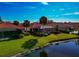 An aerial view of a home by a canal with red tile roof, screened-in pool, and lush landscaping at 616 Misty Pond Ct, Bradenton, FL 34212